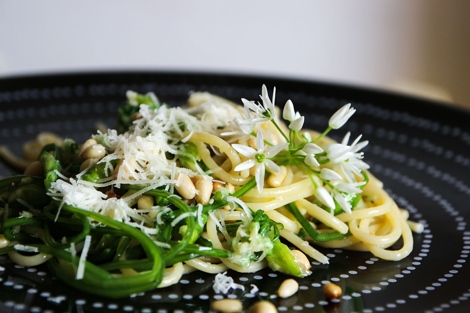 Bälauchknospen Spaghetti mit Parmesan und einer Bärlauchblüte (auch essbar)