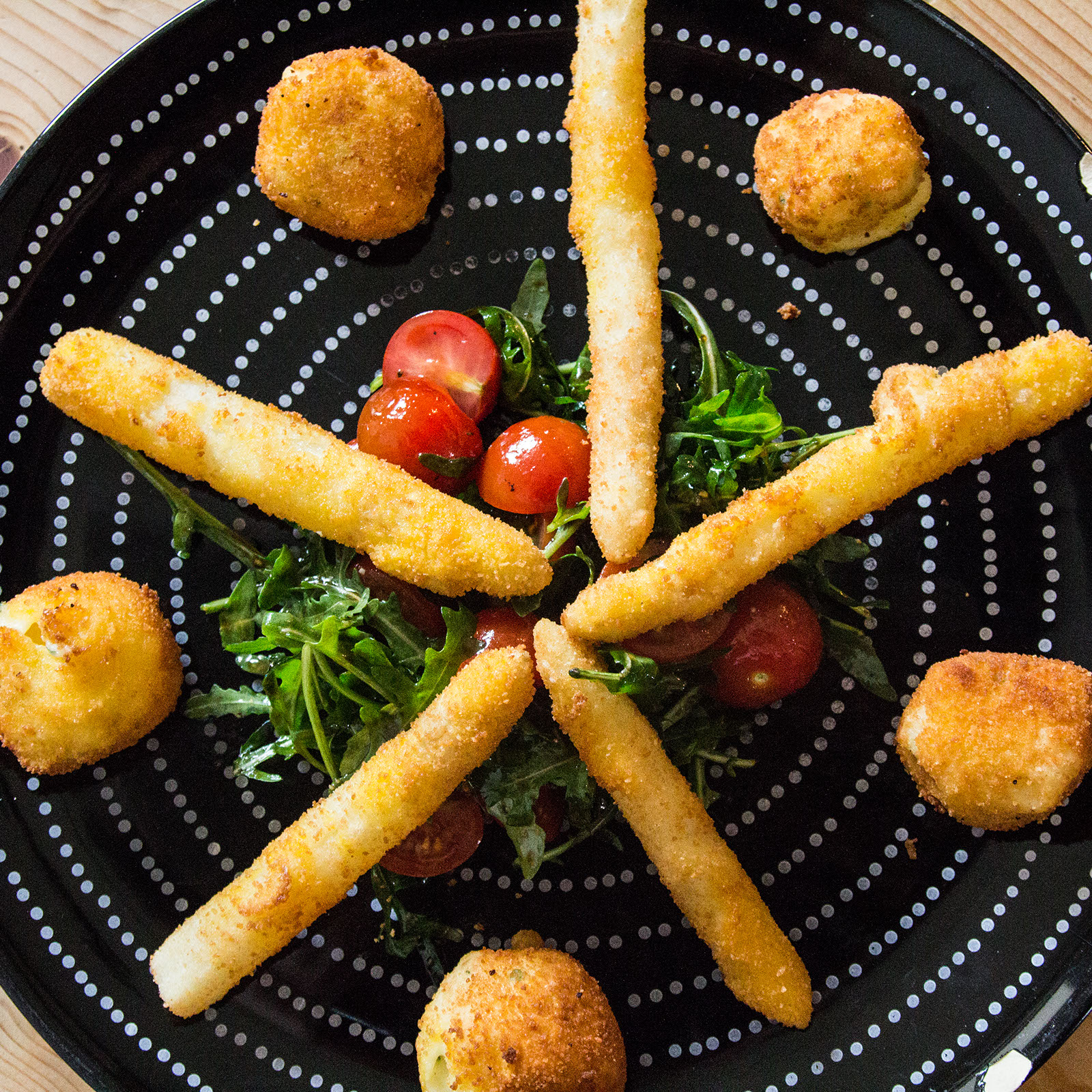 Panierte Spargelspitzen und Mozzarellabällchen auf Tomaten-Rucolasalat